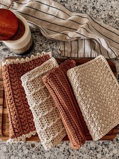 three crocheted dishcloths on a cutting board next to a wooden bowl