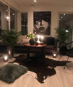 a living room filled with lots of furniture and lit candles in front of a painting