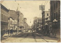 an old black and white photo of people walking down the street