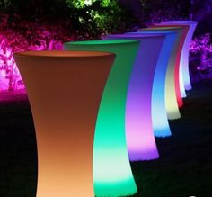 illuminated planters in the grass at night with trees and bushes behind them, all lit up