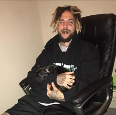 a man sitting in an office chair holding a small dog