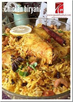 chicken biriyani in a glass bowl with lemon wedges on the side