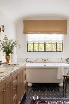 a white bath tub sitting under a window next to a sink and counter top in a bathroom