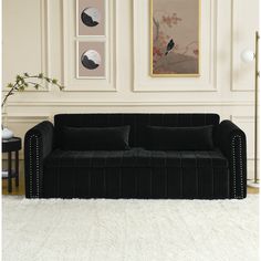 a black couch sitting in front of a white rug