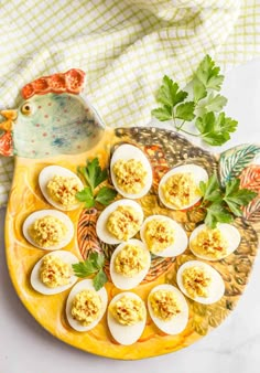 deviled eggs on a yellow platter with parsley garnish and sprig of parsley