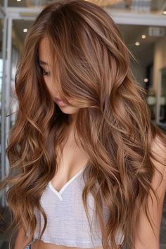 Woman with long, wavy, light brown hair standing indoors. Honey Bronze Hair, Soft Caramel Hair, Gold Caramel Hair, Warm Spring Hair Color Ideas, Caramel Hair Colour Honey Golden Brown, Honey Coloured Hair Caramel Highlights, Caramel Gold Hair, Amber Brown Hair With Highlights, Chestnut And Caramel Hair