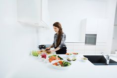 a woman preparing food in a kitchen with lots of counter space and white counterstop