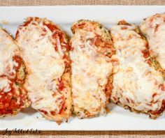 four chicken parmesan stuffed with cheese and broccoli on a white plate