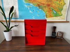 a desk with a potted plant next to it and a map on the wall