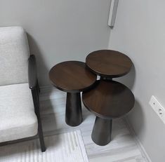 three wooden tables sitting on top of a white rug next to a chair and couch