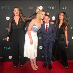 three women and one man posing for a photo on the red carpet at an event