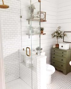 a bathroom with white walls and flooring has a glass shower door that leads to the toilet