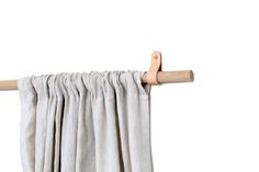 a pair of wooden clothes pins hanging from a curtain rod with white linen drapes