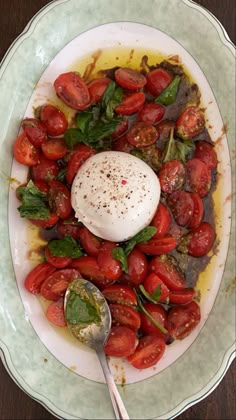 a white plate topped with lots of tomatoes and greens