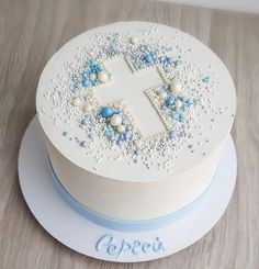 a cake decorated with blue and white beads on a wooden table next to a name plate