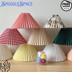 several different colored paper lamps sitting on top of a wooden table