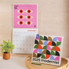 a desk with a calendar, potted plant and other items