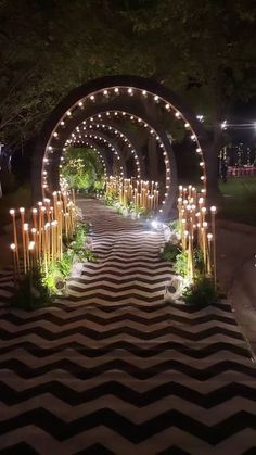 an outdoor walkway decorated with candles and greenery in the shape of trelliss