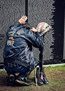 a man sitting on top of a bench next to a wall covered in writing and wearing a leather jacket