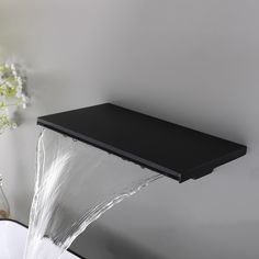 a black shelf above a white sink with water pouring from it