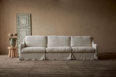 a white couch sitting next to a wooden table on top of a hard wood floor