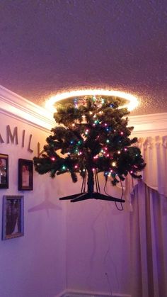 a christmas tree is hanging from the ceiling in a room with pictures on the wall