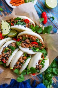 an overhead view of some tacos with meat and veggies on top, surrounded by other food items