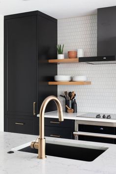 a kitchen with black cabinets and gold faucet