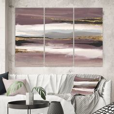 a living room with white couches and paintings on the wall above them in shades of pink