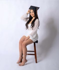 a woman sitting on top of a wooden chair wearing a graduation cap