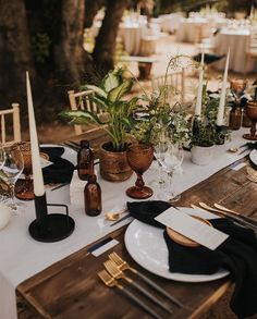 the table is set with candles, plates and place settings for an outdoor dinner party