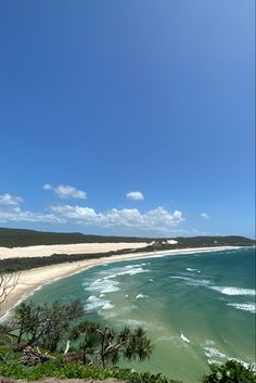 an ocean view from the top of a hill with white sand and blue sky in the background