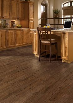 a wooden floor in a kitchen with an open laptop on the table and two chairs