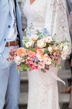 the bride and groom are holding their bouquets on the steps at this outdoor wedding