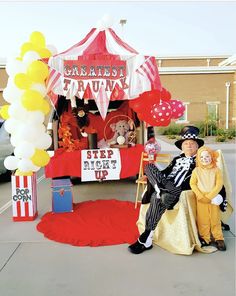 a man and woman dressed up as clowns sitting in front of a carnival booth