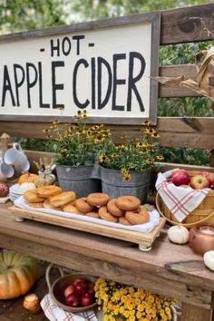 an apple cider stand with apples, donuts and other fruit on it's table