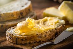 a piece of bread with butter on it next to a knife and some sliced cheese