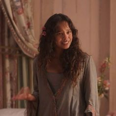 a woman standing in front of a bed with flowers on her head and arms outstretched