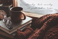 a cup of coffee sitting on top of a stack of books next to a pair of glasses