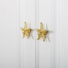 pair of gold starfish earrings on white door