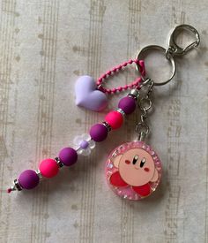 a pink pig keychain with beads and a bead around it's neck