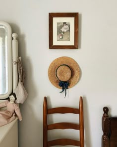 a chair with a hat hanging on the wall next to a mirror and other items