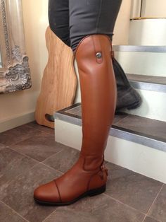 a woman standing on some steps wearing brown boots