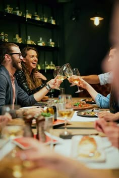 people sitting at a table toasting with wine glasses