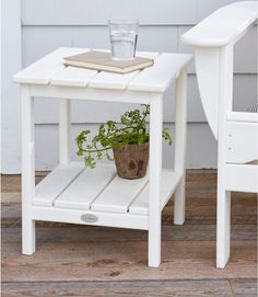 a small white table with a potted plant on it and a glass next to it