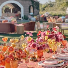 a table set with plates and vases filled with flowers