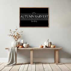 a wooden table topped with white pumpkins under a black sign that says autumn harvest