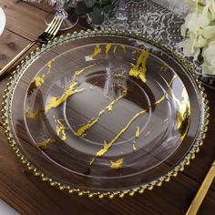 a plate with yellow paint on it sitting on a wooden table next to silverware