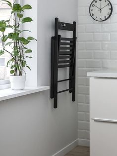 a black towel rack hanging on the side of a white wall next to a potted plant