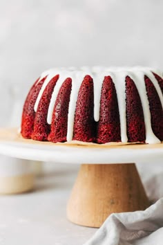 a red velvet bundt cake with white icing on a wooden platter, ready to be eaten